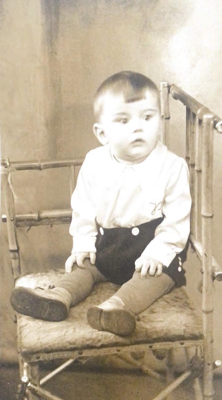 Czarno białe zdjęcie przedstawia kilkunastomiesięcznego chłopca, kt&oacute;ry siedzi na krześle.